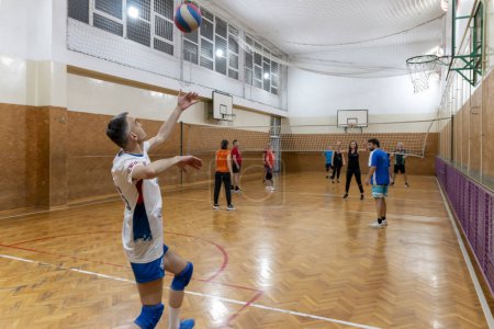 Photo for Mature man serving the ball in volleyball. Friends playing volleyball. Sport  game with group of people indoor. Belgrade, Serbia - May 10. 2024. - Royalty Free Image