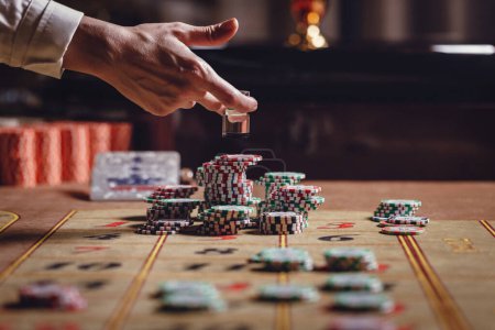 Foto de Casino, mesa de ruleta americana, el distribuidor pone Dolly en el número ganador, hay fichas en la mesa - Imagen libre de derechos