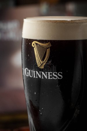 Foto de Kiev, Ucrania - 12 de abril de 2023: La famosa cerveza negra negra irlandesa Guinness en un vaso con la inscripción Guinness - Imagen libre de derechos