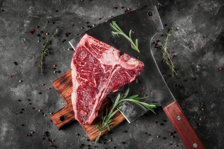 Téléchargez les photos : Porterhouse T-Bone steak marbre, viande crue steak de bœuf au romarin, poivre sur une planche de bois avec une hache de viande - en image libre de droit