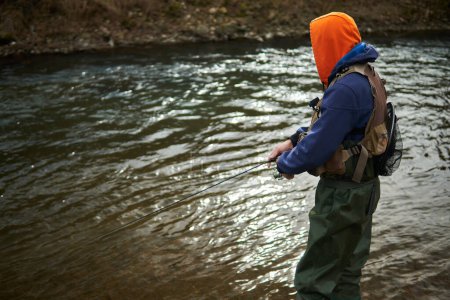 Foto de Pescador pescando junto al río durante el día con bolsa de aparejos y red - Imagen libre de derechos