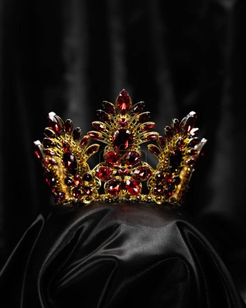 Foto de Un adorno para el cabello, una corona con una piedra roja, un símbolo de poder y belleza, sobre un fondo negro - Imagen libre de derechos