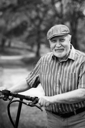 Photo for A positive, elderly man went for a walk to the park, stopped and an electric scooter was standing next to him. Summer, sunny day. Healthy lifestyle of the elderly. Black and white - Royalty Free Image