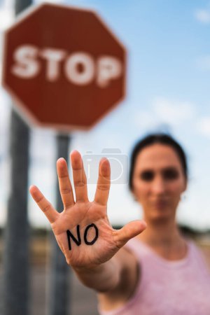 Photo for Firm woman expressing the action of enough with her hand, no or stop, no violence, no permission, no, it is no - Royalty Free Image