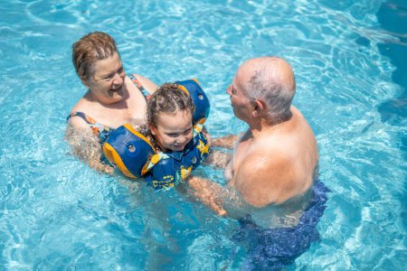 Photo for Grandparents loving and playing with their grandchild in swimming pool - Royalty Free Image