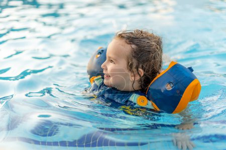 Téléchargez les photos : Beau et heureux tout-petit jouer dans la piscine avec des flotteurs extérieurs - en image libre de droit