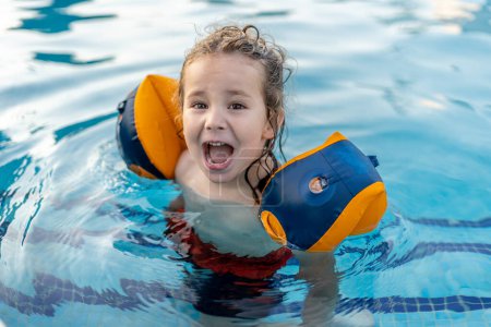 Téléchargez les photos : Beau et heureux tout-petit jouer dans la piscine avec des flotteurs extérieurs - en image libre de droit