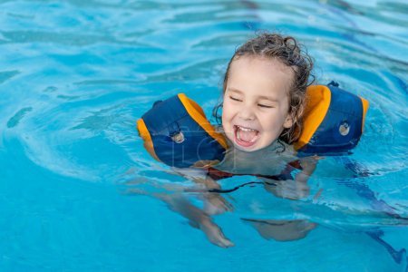 Photo for Beautiful and happy toddler playing in pool with outdoor floats - Royalty Free Image