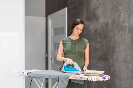 Téléchargez les photos : Jeune femme effectuant des tâches ménagères dans la cuisine, concept de style de vie - en image libre de droit