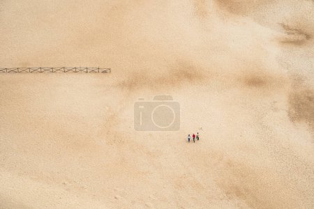 Téléchargez les photos : Vue aérienne de la plage de sable déserte avec des gens marchant - en image libre de droit