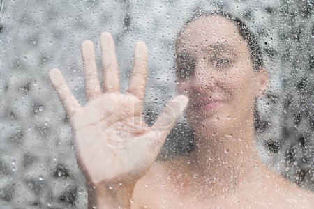 Téléchargez les photos : Femme douche à l'intérieur de la salle de bain, vue à travers le verre avec vapeur d'eau et gouttes - en image libre de droit