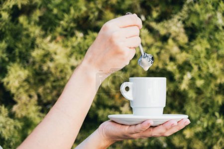 Téléchargez les photos : Femme tenant une tasse de café avec les deux mains sur fond de texture végétale verte - en image libre de droit