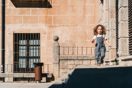 Photo for Little model boy running happy through world heritage streets in Caceres - Royalty Free Image
