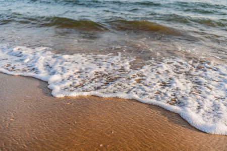 Téléchargez les photos : Gros plan de douce vague de la mer sur le rivage avec la lumière du coucher du soleil - en image libre de droit