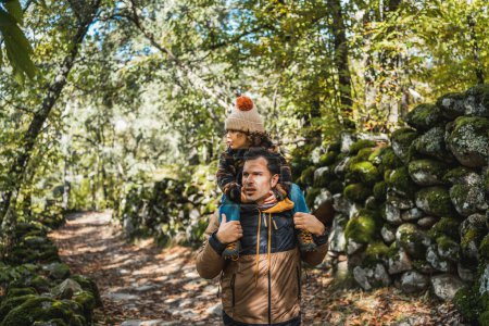 Photo for Photographer father and his fashionable son with a hat on his shoulders, happy, walking through a beautiful environment - Royalty Free Image