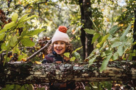 Photo for Portrait of fashionable little boy with hat playing happily on a forest path while teaching his parents about plants - Royalty Free Image