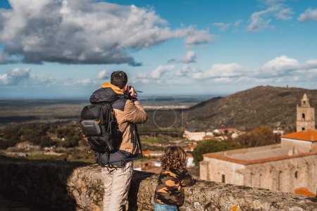Foto de Joven fotógrafo con su hijo, fotografiando una ciudad que viaja con su mochila y cámara mientras hace turismo - Imagen libre de derechos