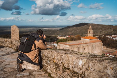 Téléchargez les photos : Portrait de jeune homme photographe, photographiant une ville voyageant avec son sac à dos et son appareil photo, vu de côté - en image libre de droit