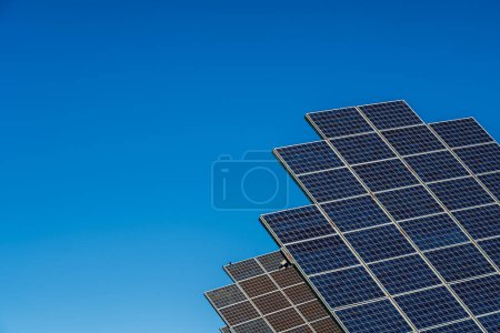 Foto de Dos filas de paneles solares en el parque solar de producción de energía fotovoltaica en el día soleado con fondo de cielo azul - Imagen libre de derechos