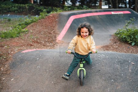 Photo for Fashionable little boy having fun on pump track circuit with his bike - Royalty Free Image