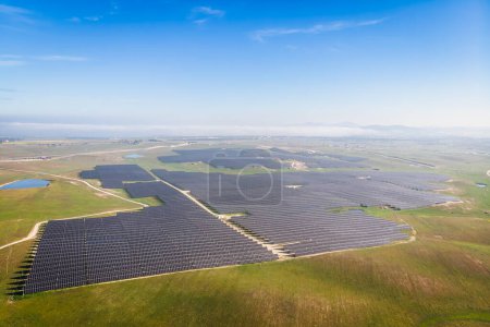 Foto de Foto aérea de la planta fotovoltaica solar bajo el cielo azul en un día soleado brillante - Imagen libre de derechos