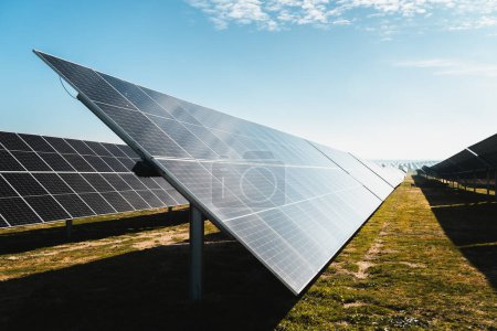 Foto de Perfil de fila de paneles solares en parque de energía solar fotovoltaica en día soleado brillante - Imagen libre de derechos