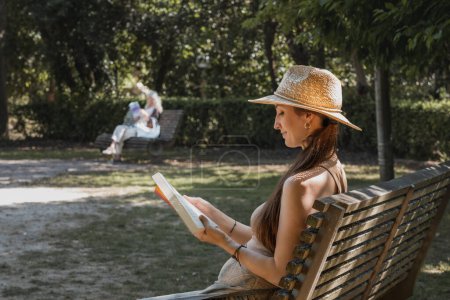 Téléchargez les photos : Femme naturelle en chapeau lisant un livre dans un bel environnement naturel vert ensoleillé - en image libre de droit