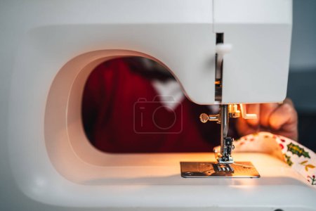 Photo for Detail of sewing machine on with light with seamstress in the background - Royalty Free Image