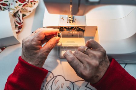 Téléchargez les photos : Détail des mains de la femme préparant le fil pour la couture sur la machine à coudre - en image libre de droit