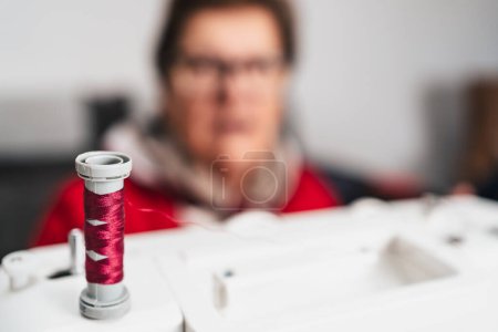 Foto de Detalle de carrete de hilo de coser rojo en la máquina de coser - Imagen libre de derechos