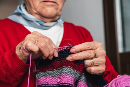 Foto de Detalle retrato de costurera manos de mujer cosiendo ropa de lana hecha a mano colorida - Imagen libre de derechos