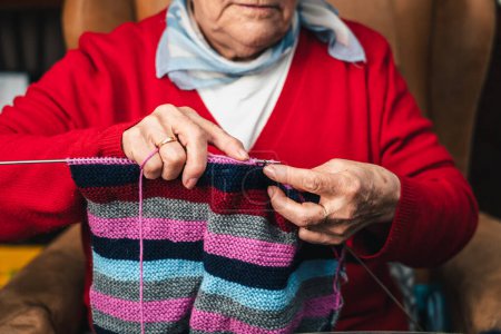 Photo for Horizontal detail portrait of hands movement of senior seamstress sewing with needles and colored wool - Royalty Free Image