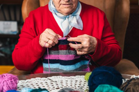 Photo for Portrait of senior woman sewing with wool on the sofa at home happy doing craft activity - Royalty Free Image