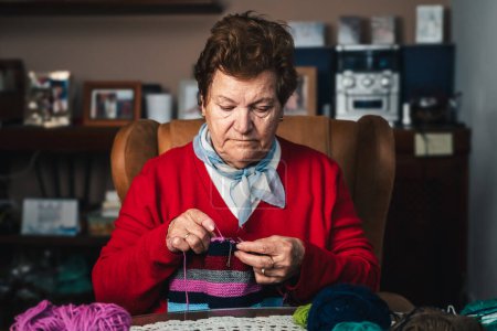 Photo for Horizontal portrait of senior woman sewing with wool on the sofa at home happy doing craft activity - Royalty Free Image