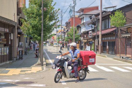 Foto de Cartero japonés en moto en las calles de Takayama en un soleado día de verano. Japón, Takayama, 08 29 2019. - Imagen libre de derechos