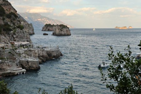 Téléchargez les photos : Marina del Cantone - 4 septembre 2023 : Restaurant Conca del Sogno, avec hôtel attenant et lido, dans la baie de Recommone au coucher du soleil - en image libre de droit
