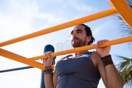 Photo for Muscular young man performing pull-ups on an exercise bar. Calisthenics concept. - Royalty Free Image