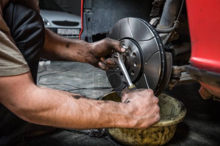 Téléchargez les photos : Homme serrant l'écrou d'un disque de frein. Concept de réparations domiciliaires. - en image libre de droit