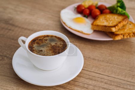 Foto de Primer plano taza de café negro con desayuno casero en mesa de madera - Imagen libre de derechos