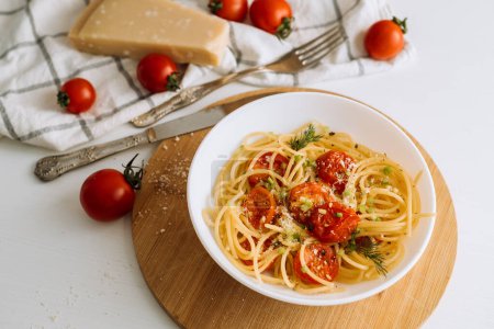 Foto de Cerrar parte de la pasta de espaguetis con parmesano y tomates cherry espolvoreado con especias en un plato sobre tabla de madera - Imagen libre de derechos