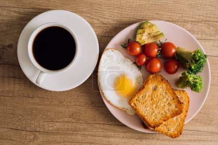 Foto de Flat poner desayuno casero con taza de café negro, huevo frito y tostadas con tomates y aguacate en el plato - Imagen libre de derechos