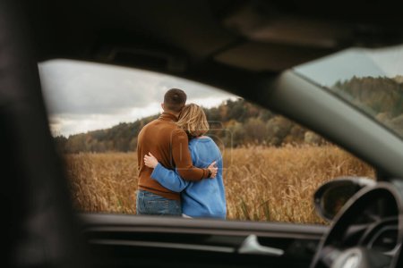 Foto de Vista a través de la ventana del coche, un hombre y una mujer se abrazan, pareja adulta disfrutando de su viaje por carretera - Imagen libre de derechos