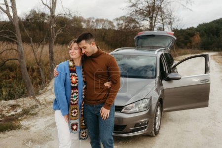 Foto de Un hombre y una mujer en un coche en el camino de tierra, pareja adulta en viaje de otoño - Imagen libre de derechos