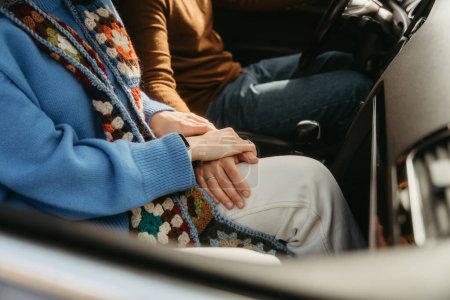 Foto de Dos individuos están sentados en un vehículo, con los dedos entrelazados, mostrando un gesto de comodidad y conexión mientras viajan juntos. - Imagen libre de derechos