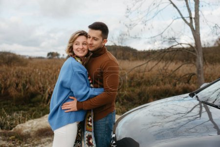 Foto de Feliz hombre y mujer se abrazan delante de un coche, con sonrisas en sus rostros - Imagen libre de derechos