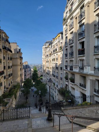 Foto de Vista de la calle parisina en Montmartre. Edificios elegantes con techos azules, adornados con balcones llenos de flores. En esta imagen del encanto parisino, cada paso es un viaje a través de la belleza y la historia. París, Francia - Imagen libre de derechos