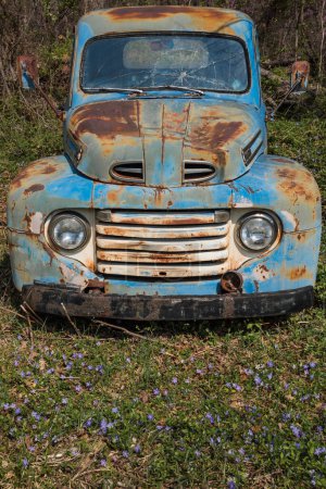 Abandoned old blue car in a field with wildflowers and grass. High quality photo