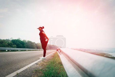 Téléchargez les photos : Les femmes se réchauffent avant de courir sur la route, fixe un nouvel objectif pour commencer à courir exercice, sélectif et soft focus. - en image libre de droit