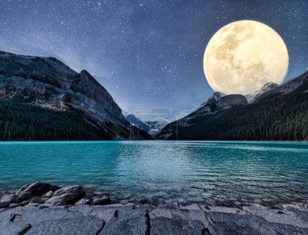 Photo for Big moon glowing over rocky mountains and starry on Lake Louise in the night at Banff national park, AB, Canada - Royalty Free Image