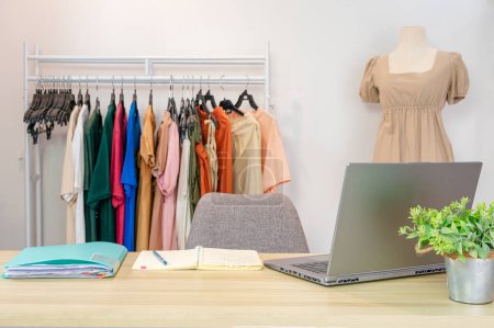 Foto de Online female clothes shop with laptop, notebook, document file on desk and casual cloth on clothes line and mannequin in the office - Imagen libre de derechos